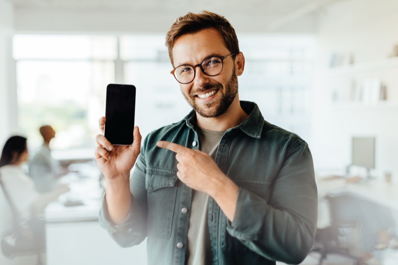 Person im Büro zeigt auf ein Smartphone